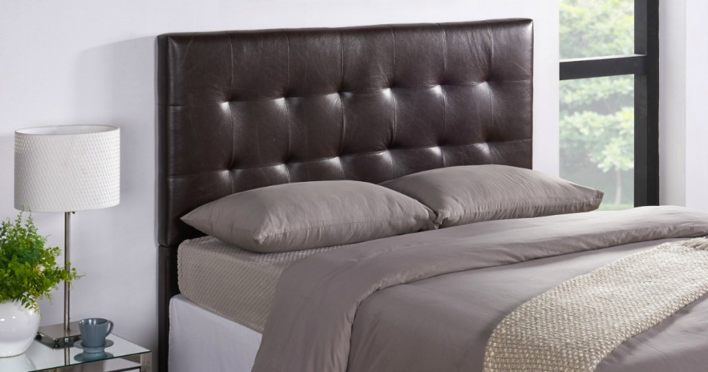 Queen sized bed with leather headboard and gray satin sheets