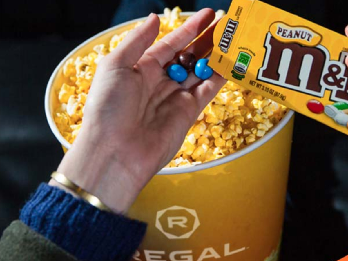 person holding M&M's and popcorn in Regal Cinemas