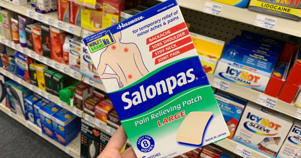 Hand holding Salonpas in from of shelf
