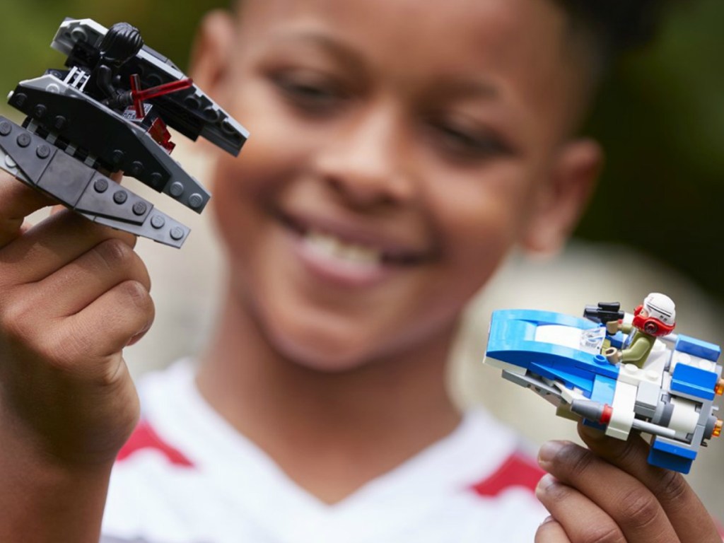 Boy playing with two Star Wars LEGO Ships 