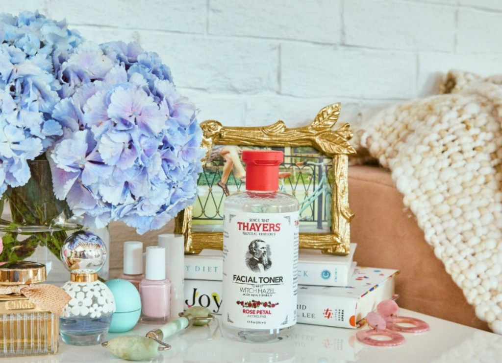 Thayers Rose Petal Witch Hazel & Aloe Vera Toner 12oz Bottle on counter surrounded by beauty items, hydrangeas and a jade roller
