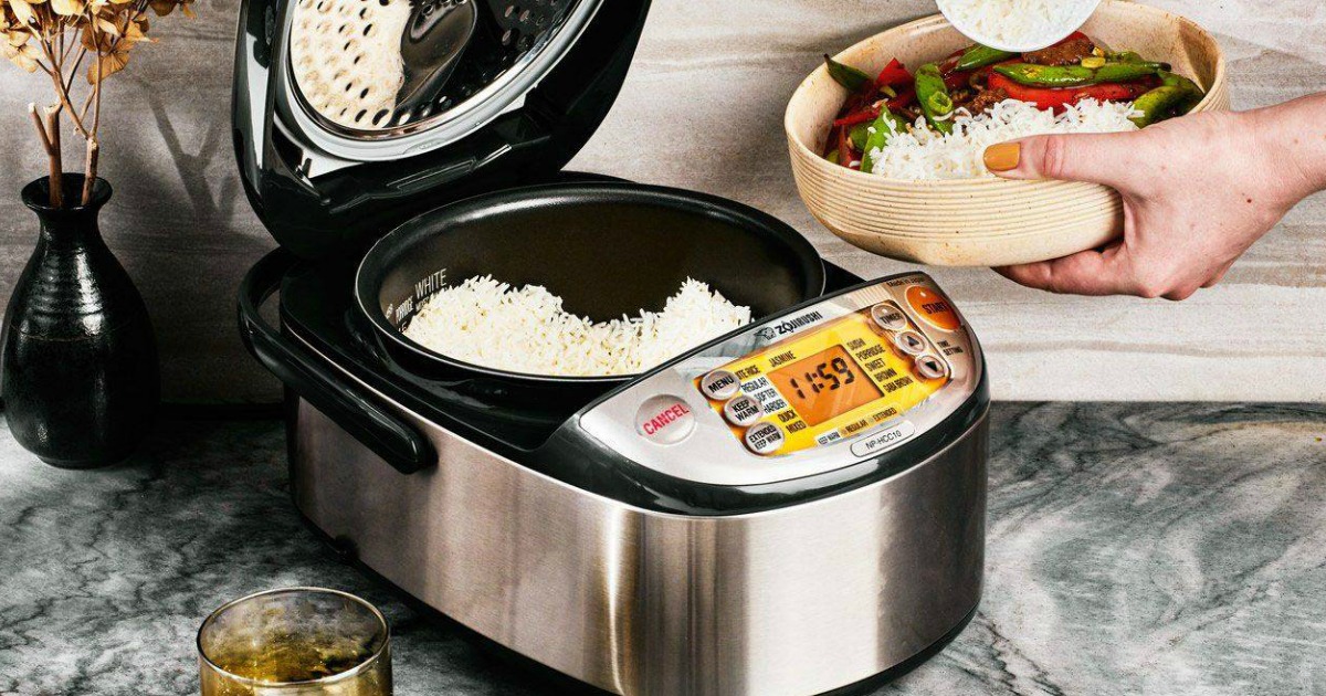 person holding a bowl of rice and vegetables next to a Zojirushi Rice Maker