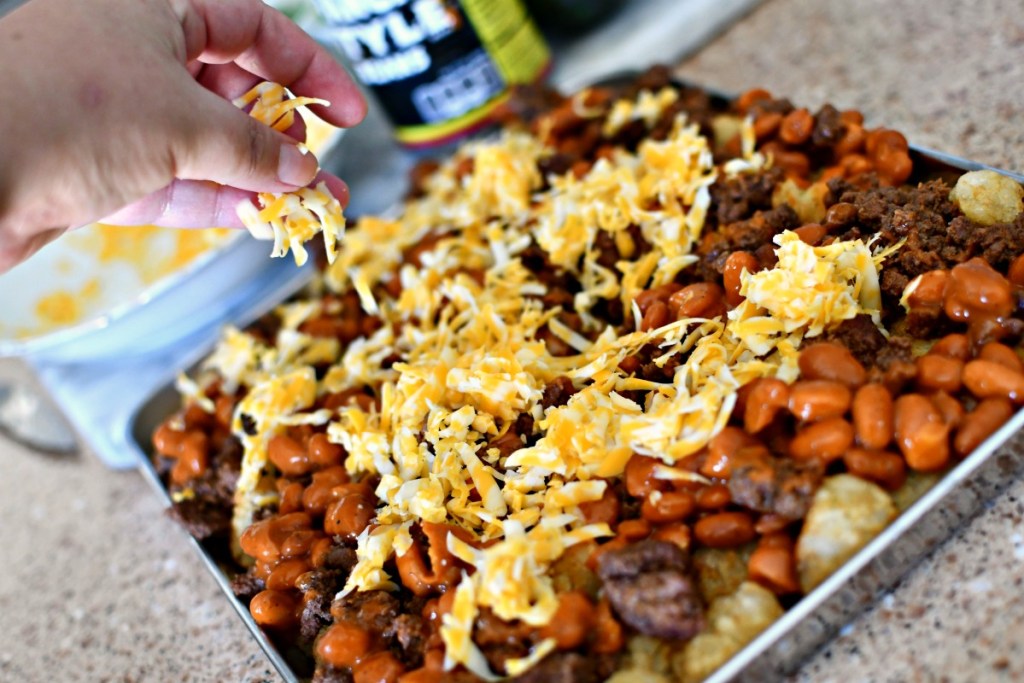 adding shredded cheese to totchos