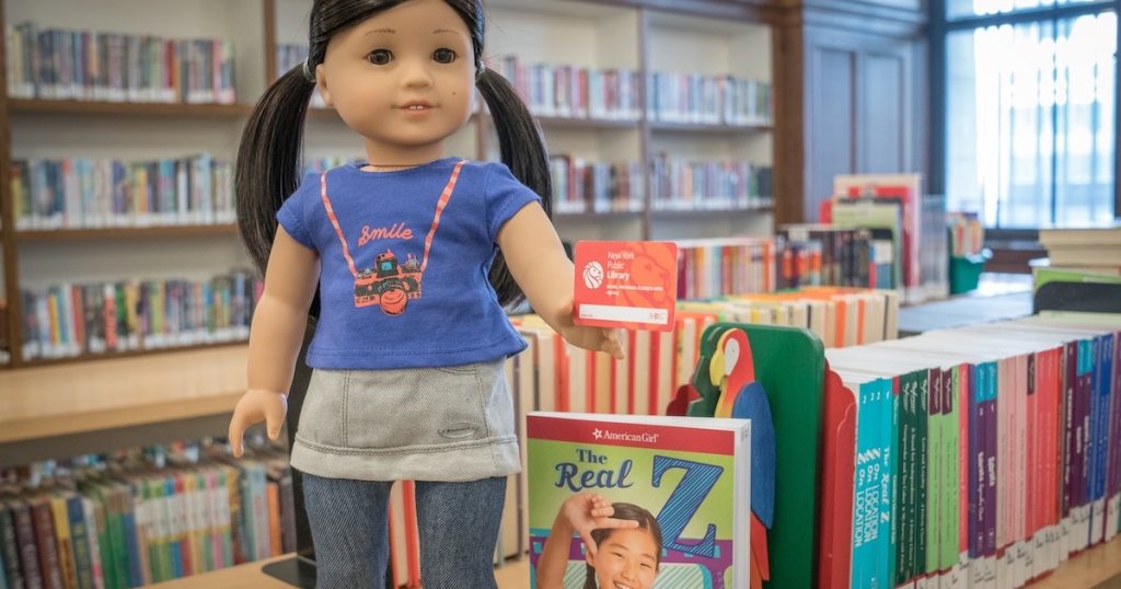 American Girl doll standing on library books shelf