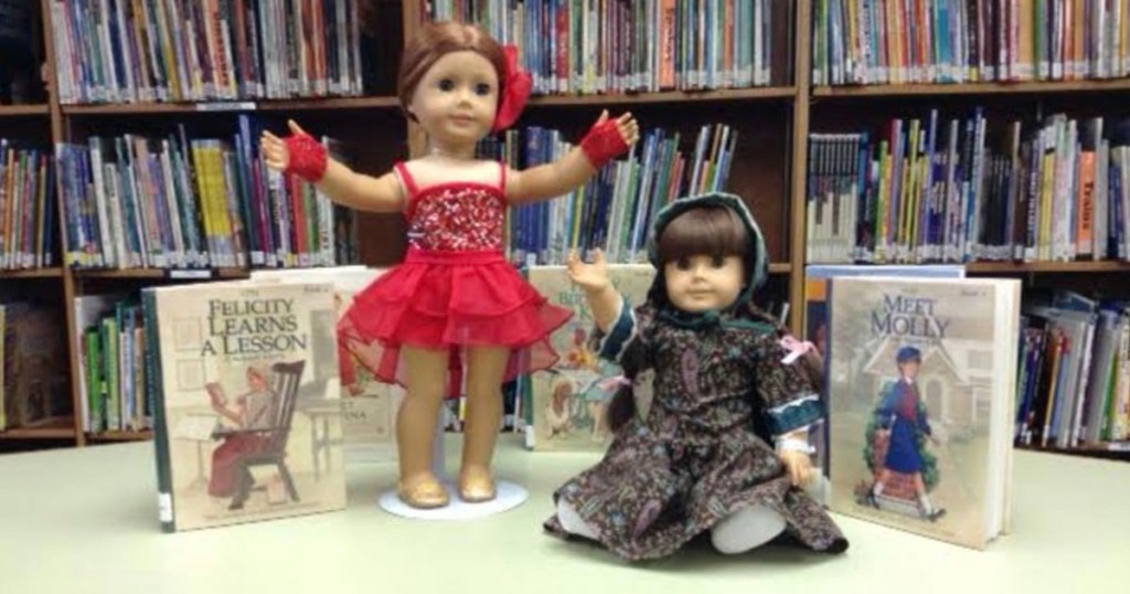 two American Girl dolls on library table with books