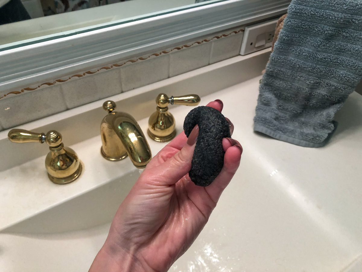 hand squeezing sponge with sink in background