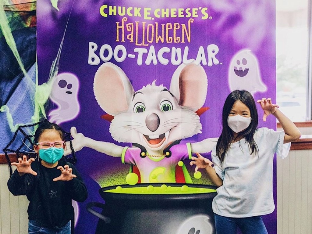 girls standing in front of Chuck E Cheese cauldron