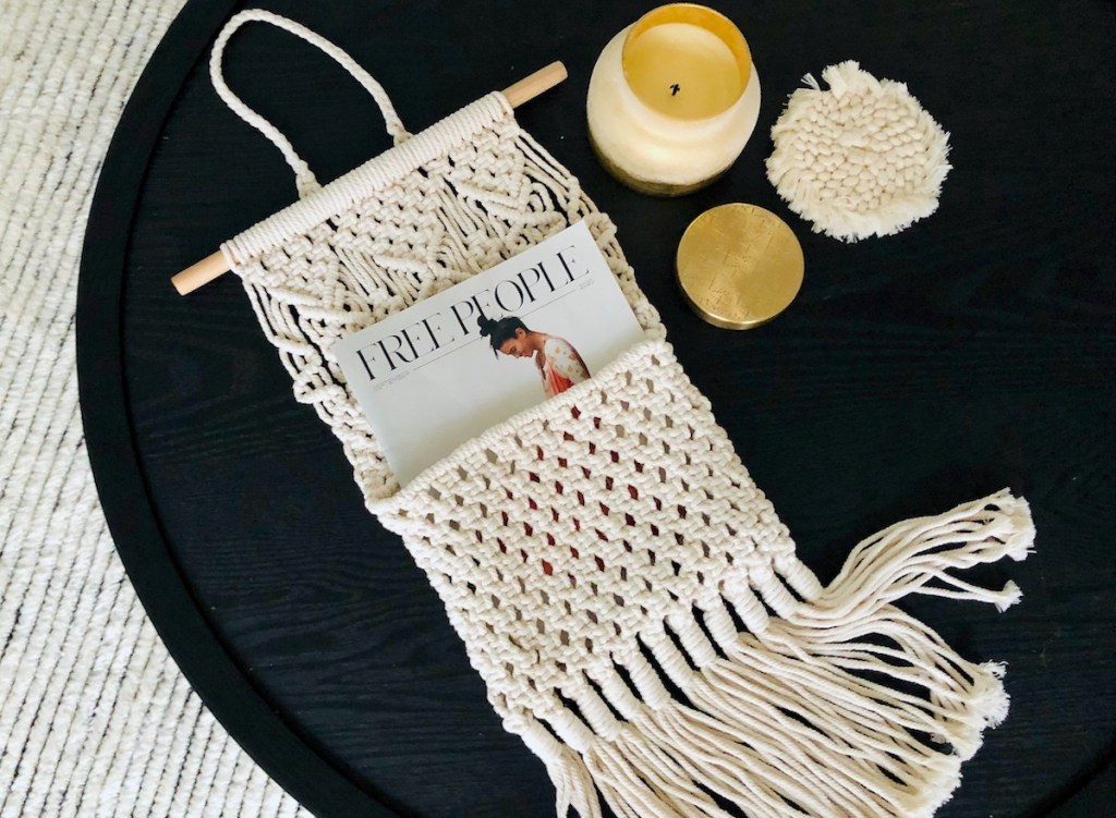 macrame hanger on black table with candle and magazine