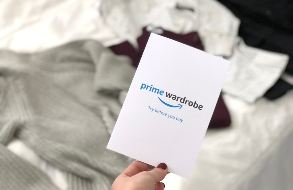 hand holding prime wardrobe card with clothes in background