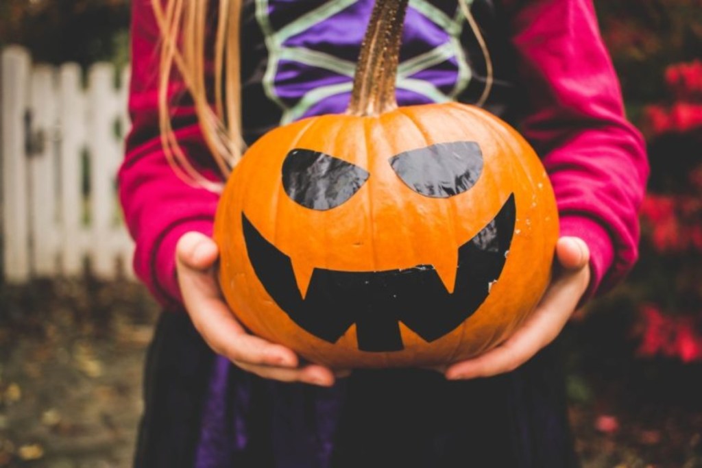 girl in costume holding Jack O Lantern