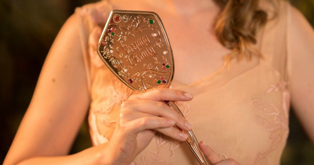 woman holding hand mirror in a gold color