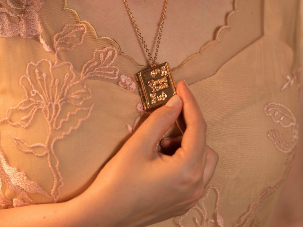 woman holding necklace that looks like a book