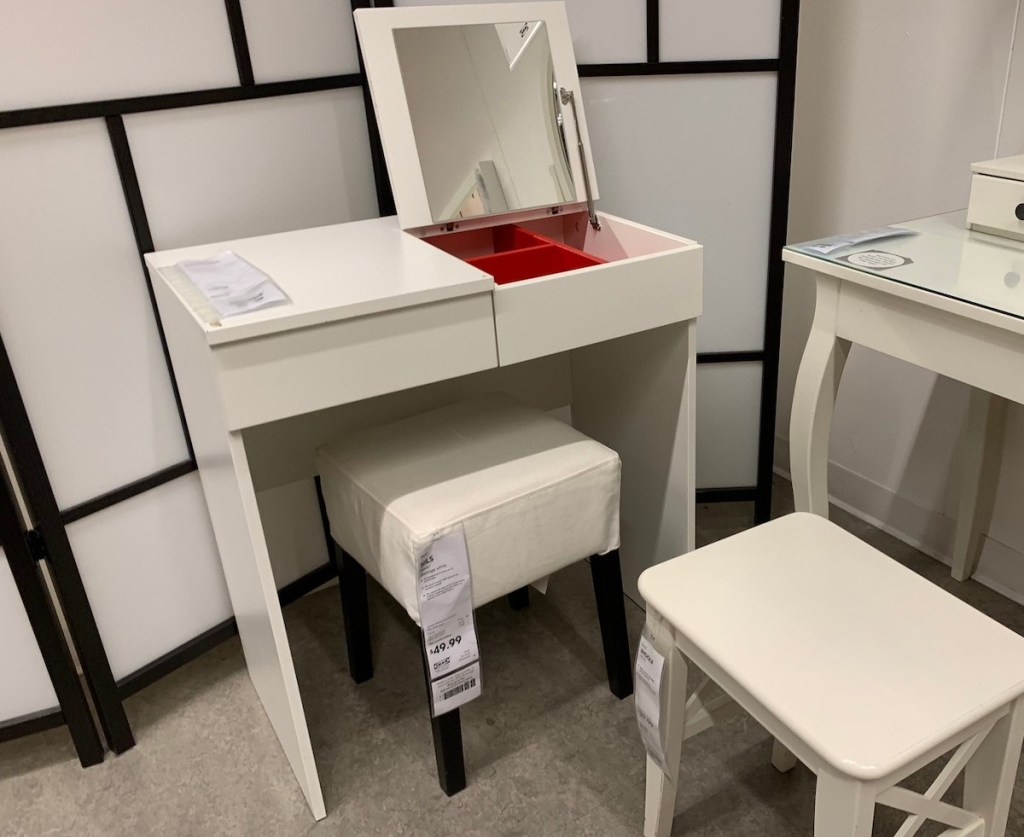 small white makeup vanity with open lid and white stools