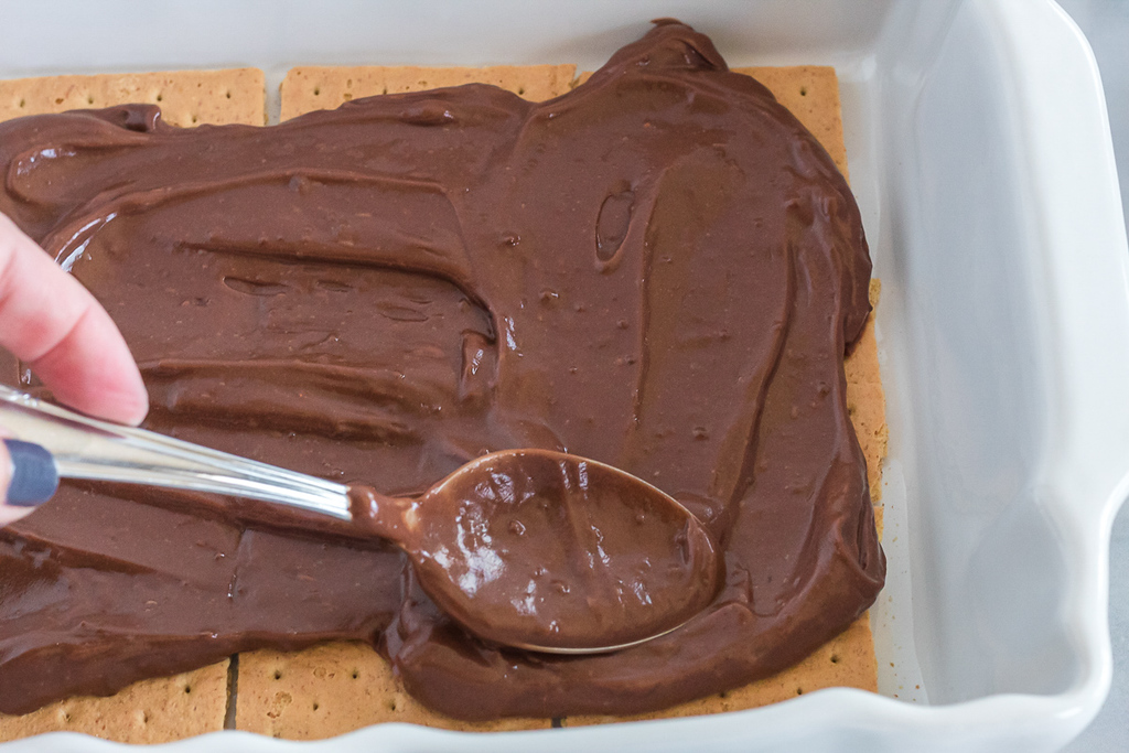 spreading chocolate pudding over graham crackers with spoon