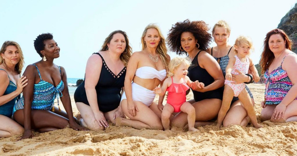 women on beach wearing swimsuits with baby