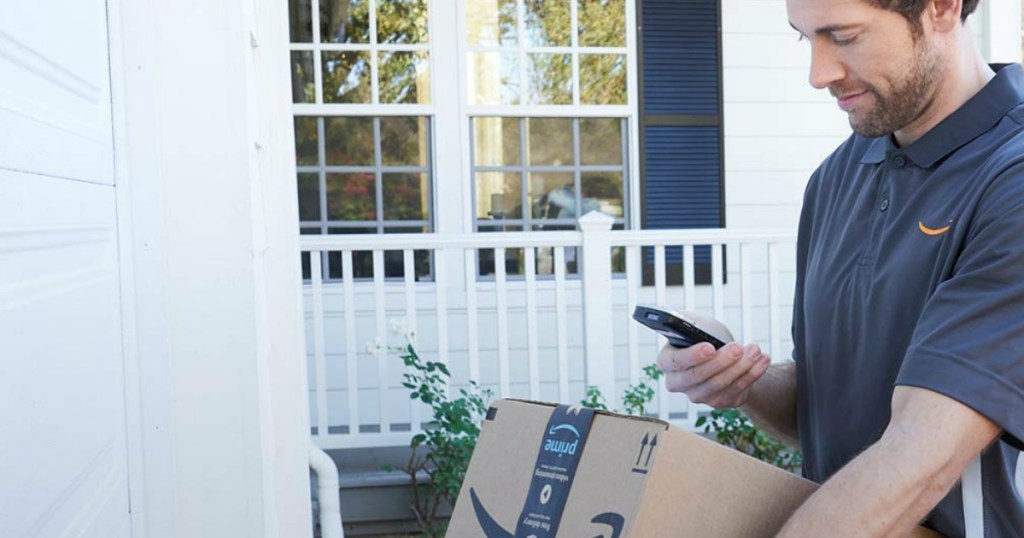 man checking smartphone while holding an Amazon box