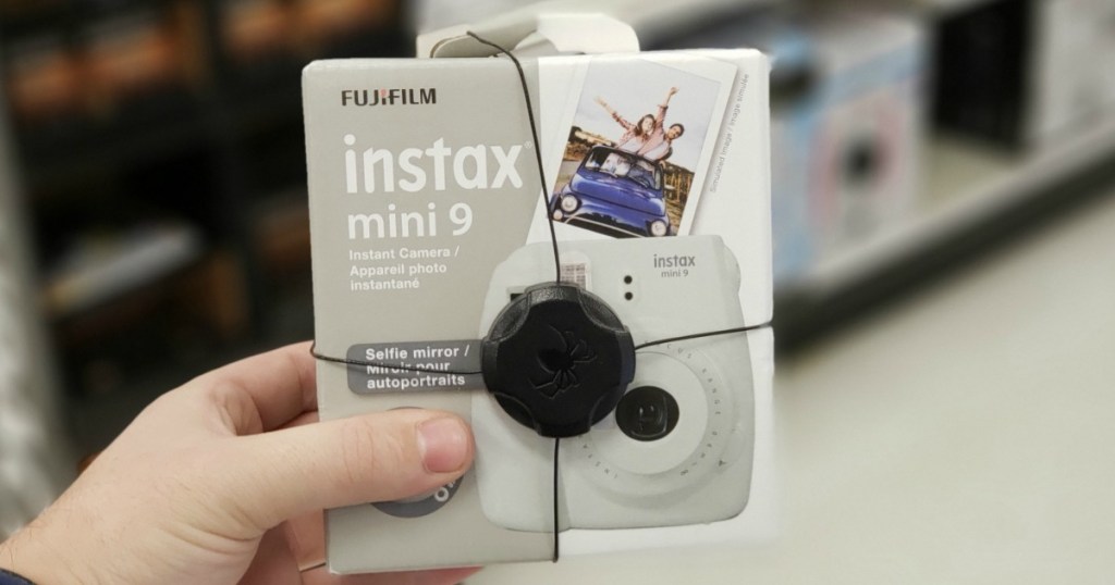 Hand holding a white Instax Mini 9 in packaging in-store
