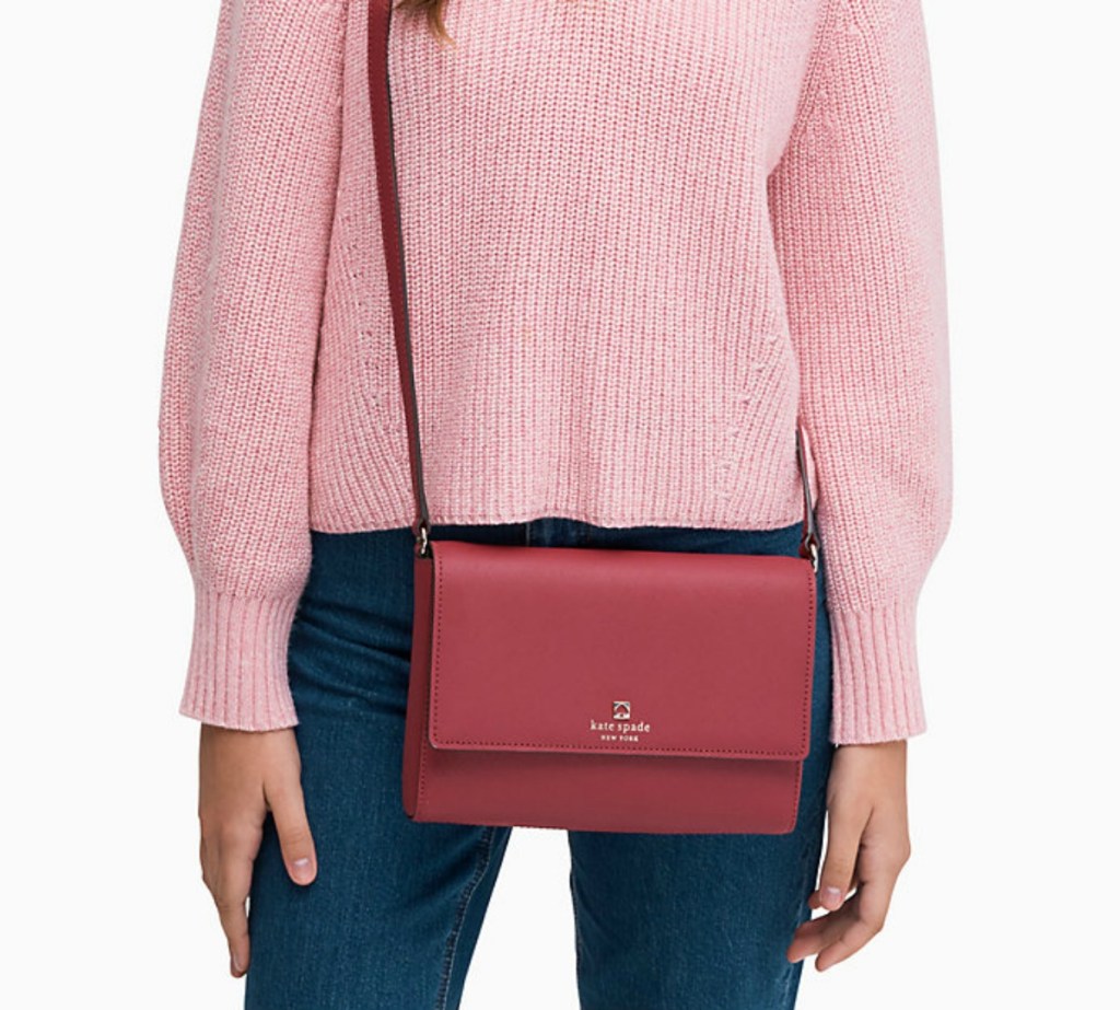 woman in pink sweater and jeans wearing dark pink Kate Spade bag