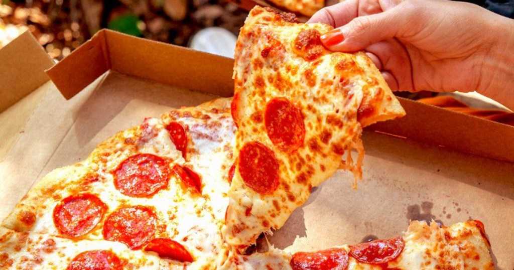 hand holding slice of little caesar pepperoni pizza