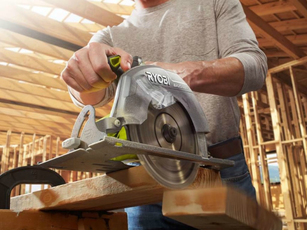 Man using a Ryobi Power Saw on a large piece of wood in a workshop