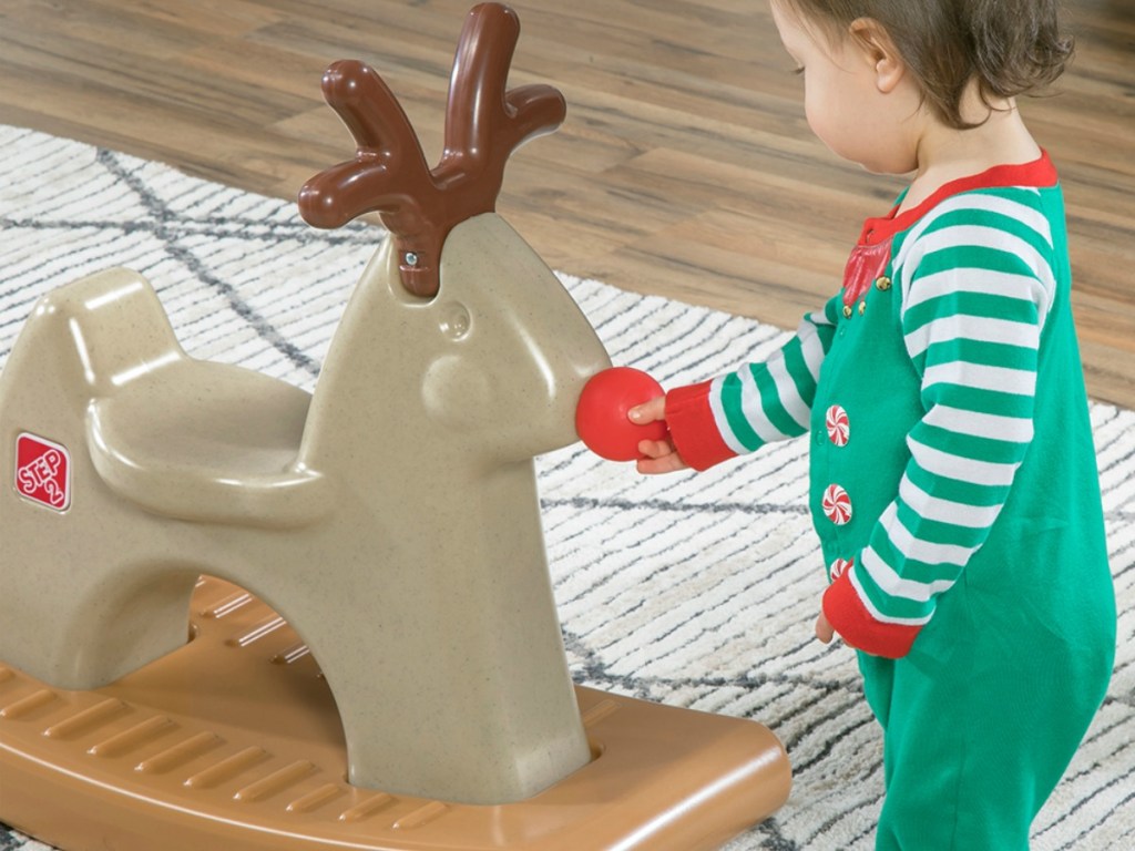 Small child looking at a rocking reindeer toy