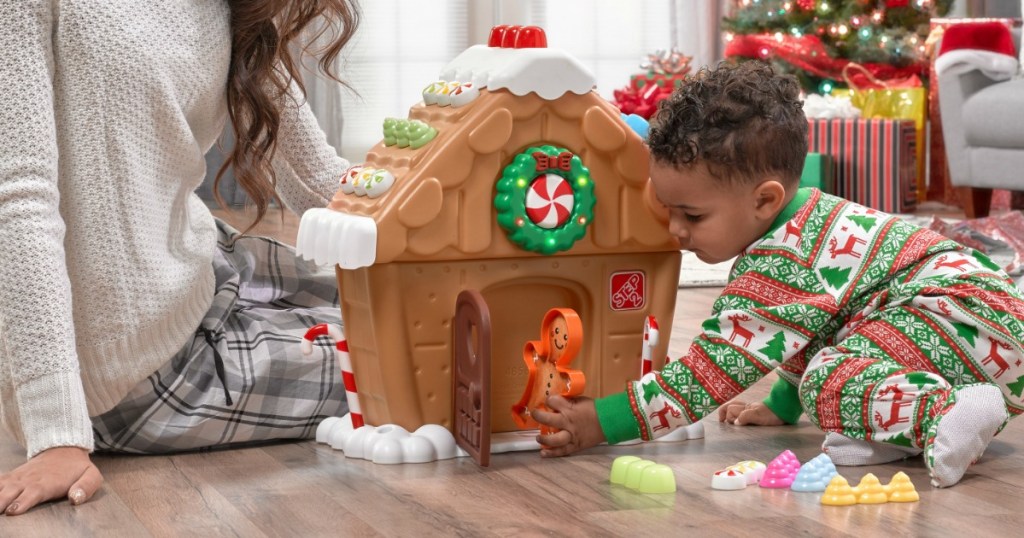 little kid playing with plastic gingerbread house