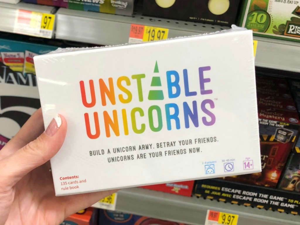 Woman holding a package of the Unstable Unicorns card game in-store