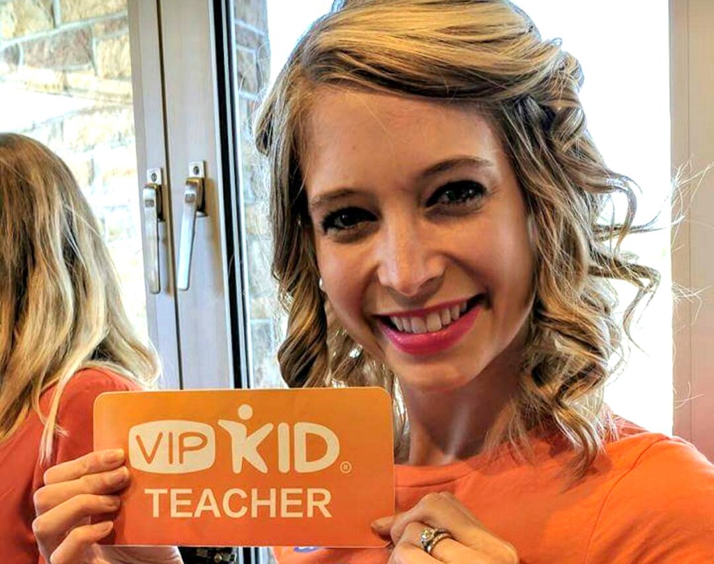 woman holding VIP Kid teacher sign smiling