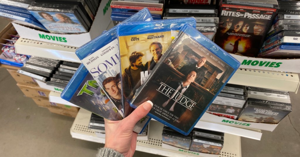 hand holding up four movies at dollar tree