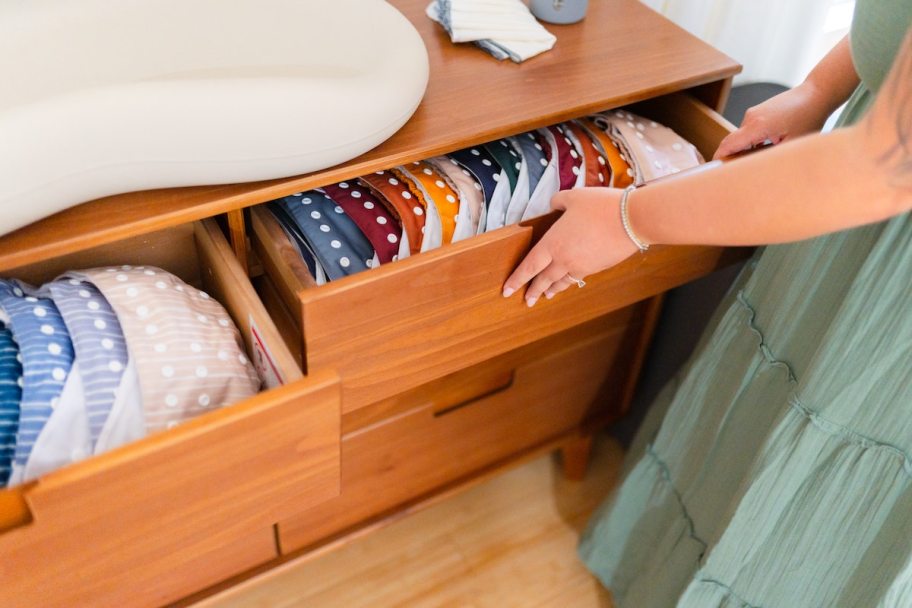 woman pulling open drawer with colorful cloth diapers inside