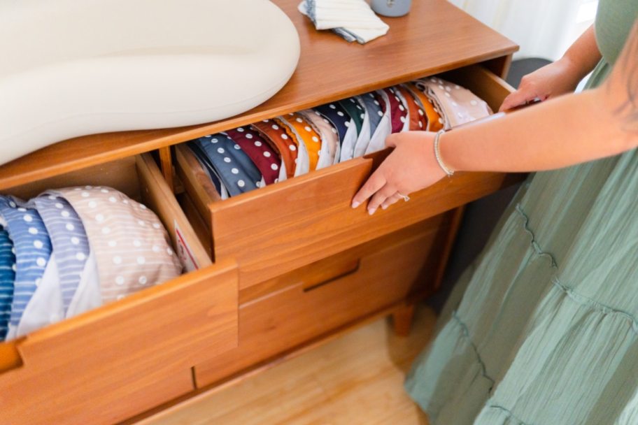 woman pulling open drawer with colorful cloth diapers inside