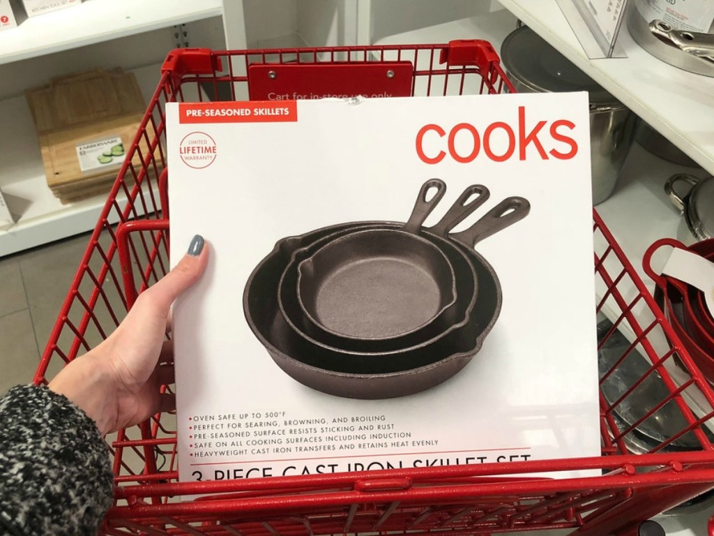 hand holding box with fry pans in shopping cart