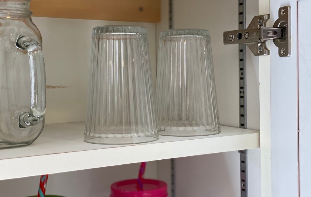 two clear drinking glasses upside down in kitchen cabinet