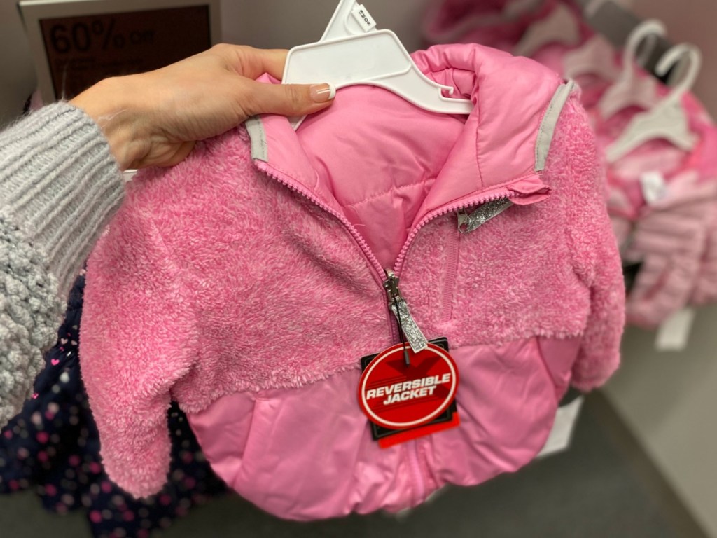 hand h olding pink jacket by store display