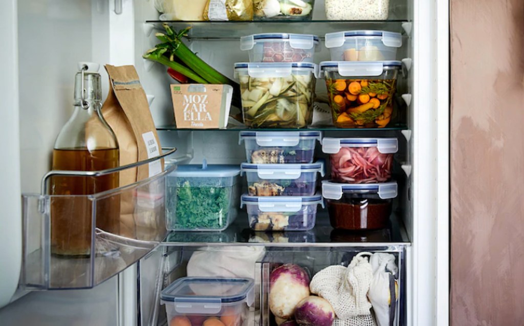 refrigerator with stacked glass containers inside containing leftover recipes