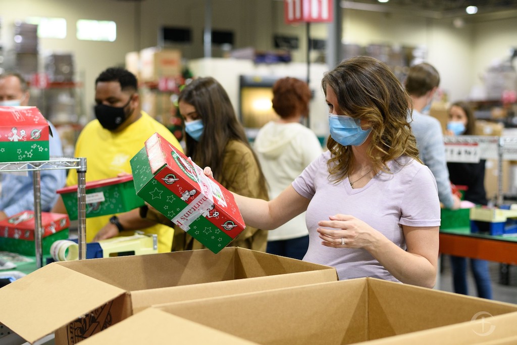 people with masks on packing Operation Christmas Child boxes 