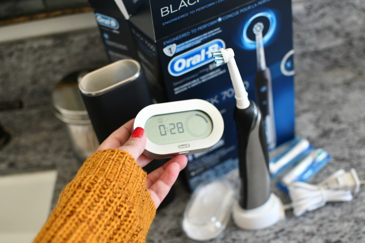 hand holding oral-b 7000 toothbrush and brushing timer