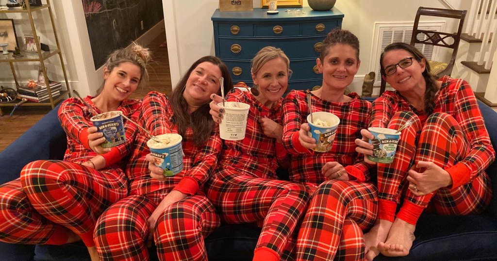 Hip team sitting on couch in matching plaid pajamas eating ice cream