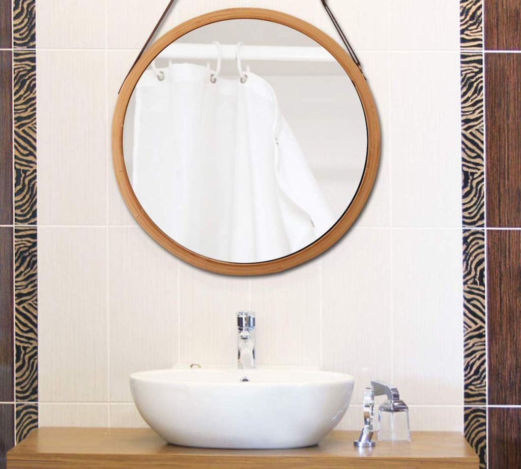 round mirror hanging over white bathroom sink 