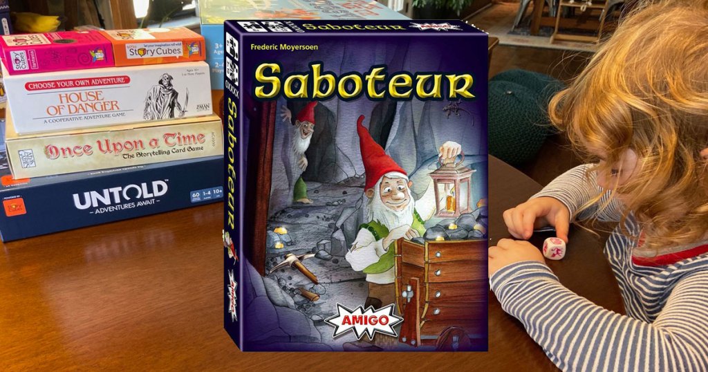 little girl at a table of games with focus on Saboteur Miners and Dwarves Strategy Card Game