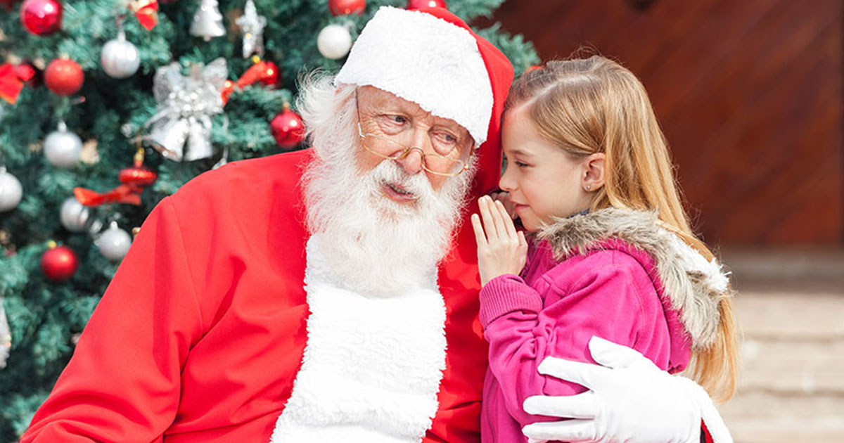 child whispering a secret to Santa Claus