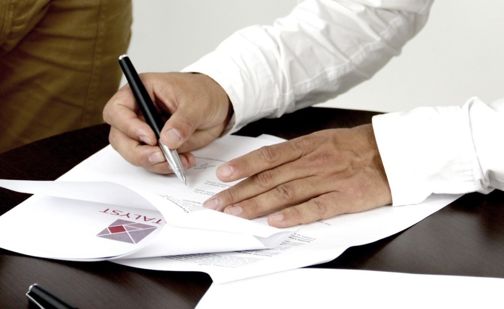 man signing packet of papers