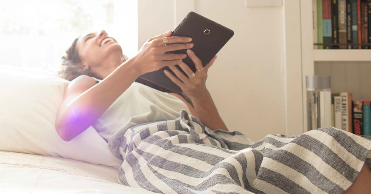 woman looking at tablet on bed