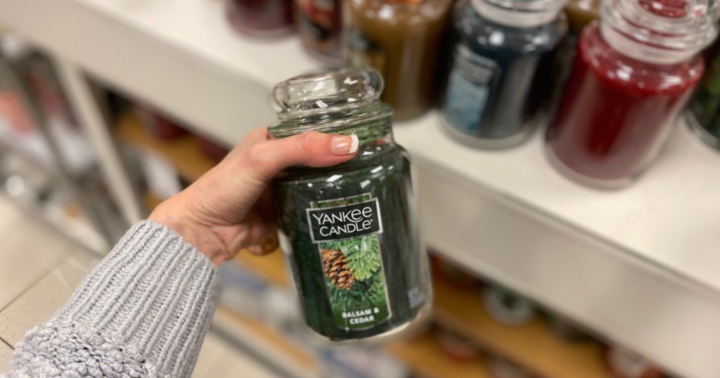 woman holding yankee candle with candles in background