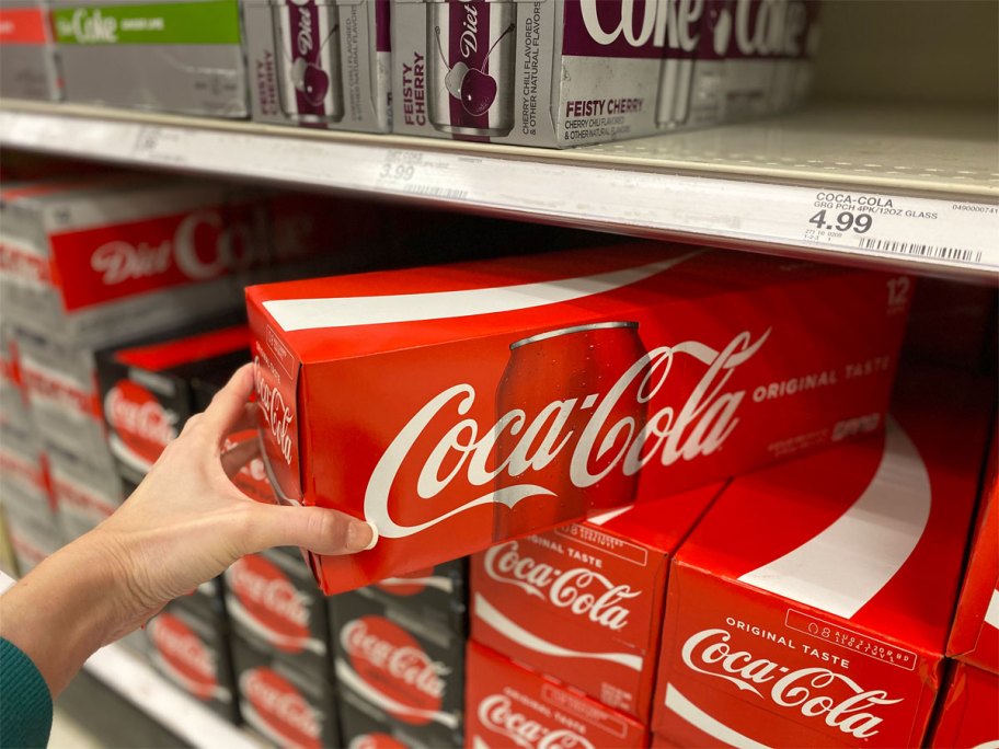 hand holding a case of coke