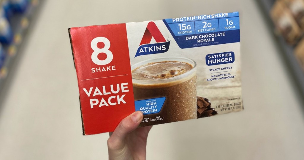 lady holding an eight count pack of Atkins shakes 