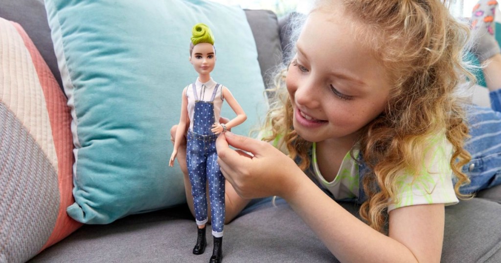 Young girl playing with a Barbie Fashionista doll on the sofa