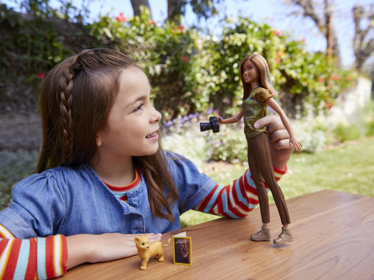 little girl playing with barbie outside