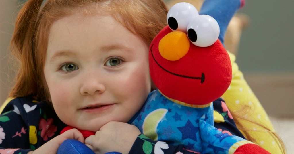 Little girl holding onto a bedtime Elmo doll