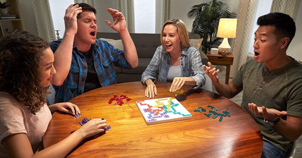 four adults playing blokus game at table
